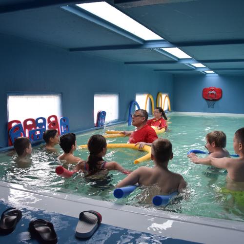 Innenansicht eines Schwimmcontainers mit Kindern und einem Schwimmlehrer