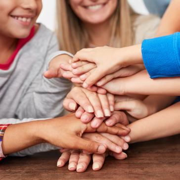 Eine Gruppe von Kindern, die gemeinsam mit ihren Händen einen Stapel bilden